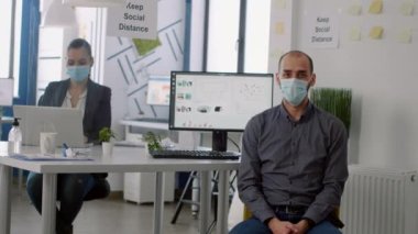 Şirket ofisinde otururken koruyucu maskeli bir iş adamının portresi