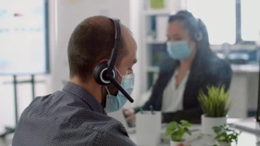 Koruyucu yüz maskeleri ve kulaklık takan iş adamları.