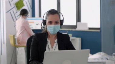 Koruma maskeli iş kadını mikrofona konuşuyor.