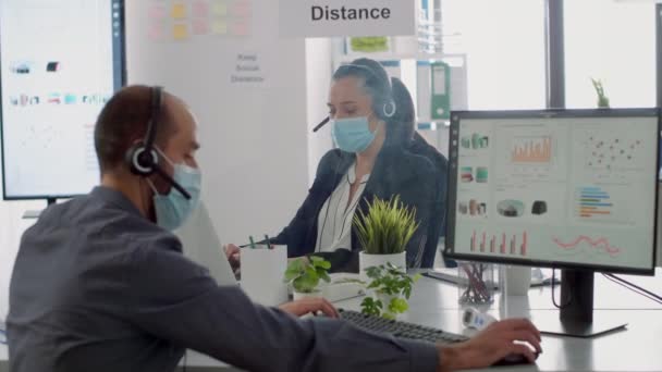 Equipe de negócios com fone de ouvido conversando em microfone enquanto verifica estatísticas financeiras — Vídeo de Stock