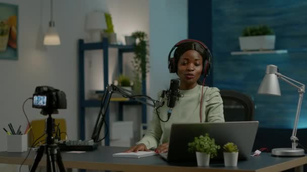 Africaine des médias sociaux femme regardant dans un ordinateur portable parler au microphone — Video