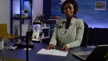 Gülümseyen Afrikalı kadın telefon kamerasının önünde oturuyor.