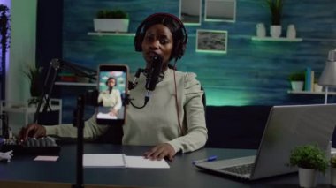 İçerik oluşturucu mikrofon kontrolünde konuşurken kameraya bakıyor