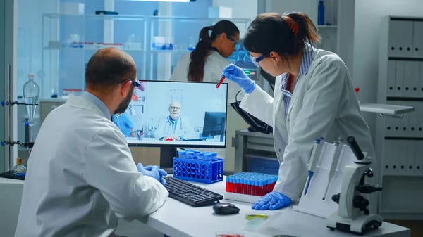 Tecnici di laboratorio che parlano in videochiamata con un medico chimico professionista — Foto Stock