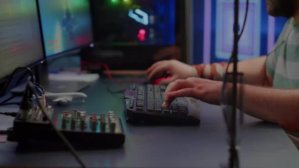 Primer plano de streamer escribiendo en el teclado RGB jugando juego de disparos de espacio — Vídeo de stock