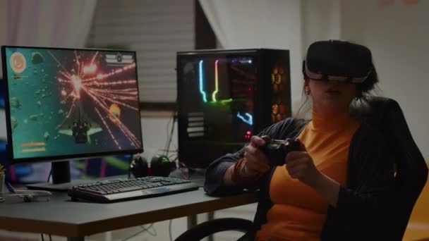 Через плечо сфокусированного кибер-игрока, носящего гарнитуру виртуальной реальности проигрывая игру — стоковое видео