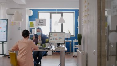 Tıbbi maskeli iş kadınları yönetim istatistikleri hakkında konuşuyor