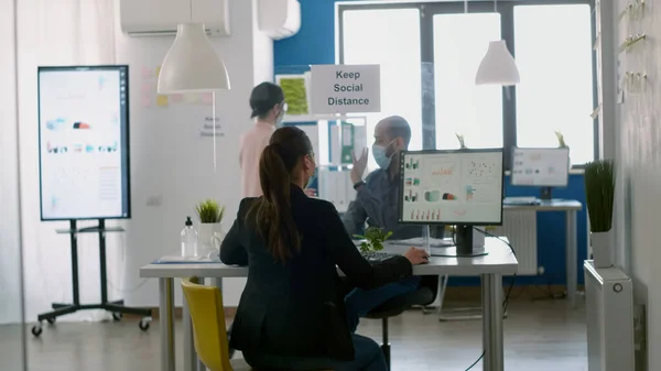 Coworkers wearing face masks greeting each other with elbow