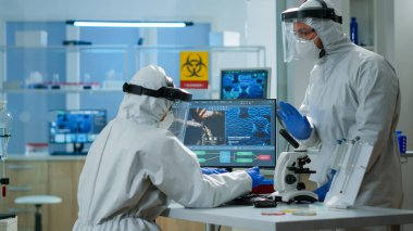 Pen giysili kimyager kadın virüs gelişimini bilgisayarda kontrol ediyor.