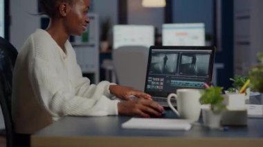 Siyahi bir kameraman profesyonel dizüstü bilgisayarda film düzenliyor.