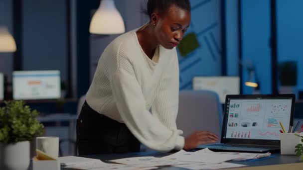 Стрессовый африканский менеджер женщина читает доклады, стоя за столом — стоковое видео