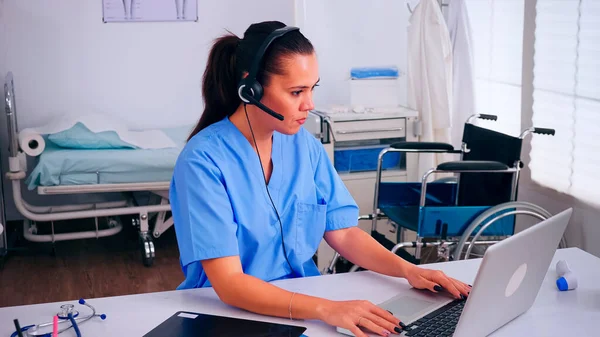 Receptionist, operator speaking online with patients using headphone