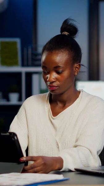 African manager woman using laptop and tablet in same time working overtime