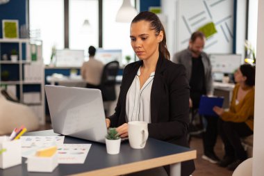 Konsantre iş kadını dizüstü bilgisayara mali raporlar yazıyor.