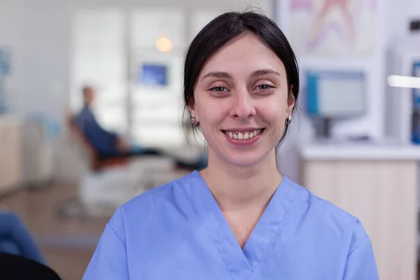 Enfermera sonriente de estomatología mirando la cámara en el consultorio del dentista — Foto de Stock