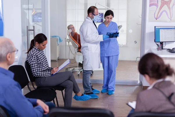 Dentist finishing teeth treatment for old man