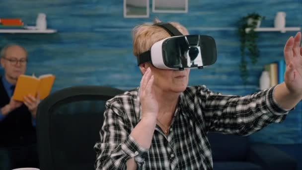 Aposentada mulher idosa concentrada usando óculos de realidade virtual na sala de estar — Vídeo de Stock