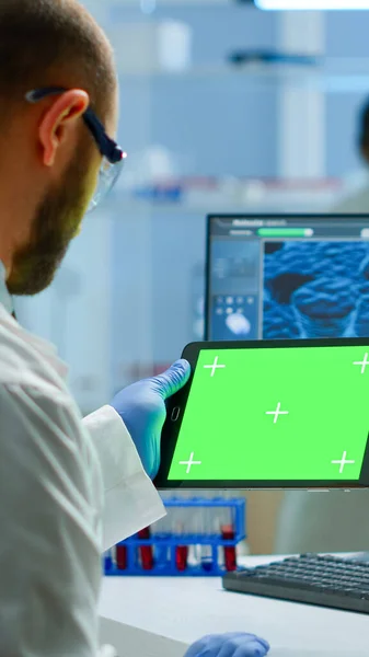 Researcher holding and looking at tablet with chroma key