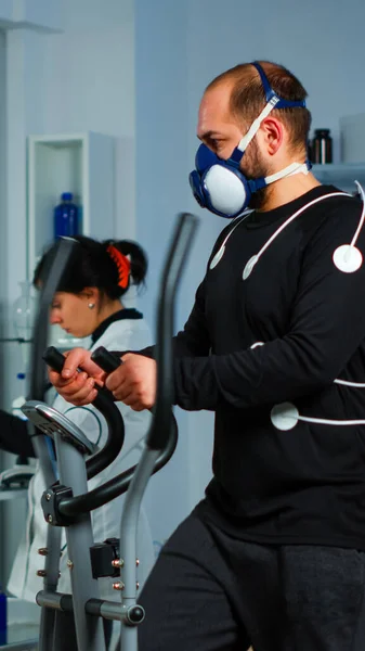 Sportsman running on cross trainer in lab facility for sports performance