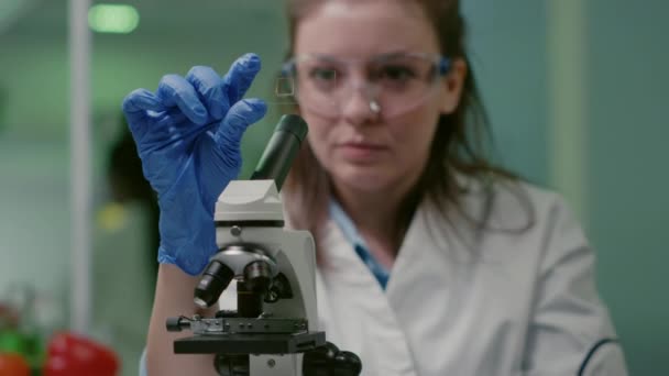 Closeup of scientist woman looking at test sample of lea — Stock Video