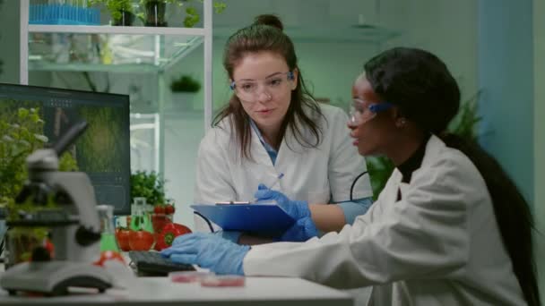 Два коллеги проверяют образец веганской экспертизы в области биотехнологии письма мяса. — стоковое видео