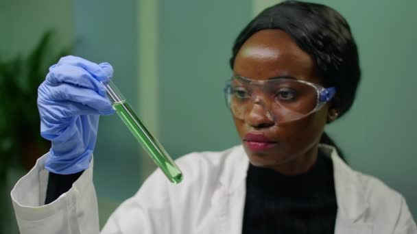 Біологічна жінка тримає пробну трубку з генетичною рідиною, яка вивчає зелений зразок ДНК — стокове відео