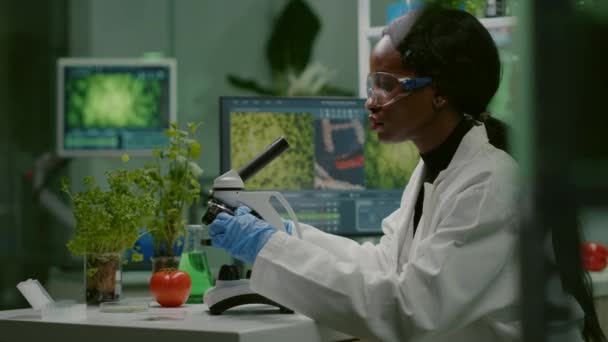 Mujer bióloga mirando la muestra de prueba bajo el microscopio — Vídeo de stock