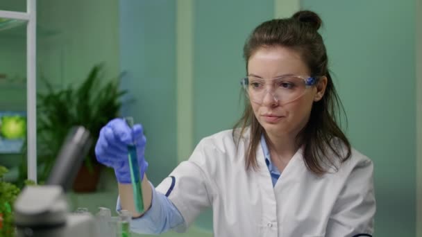 Хімік дивиться на пробірку з генетично модифікованою рідиною — стокове відео