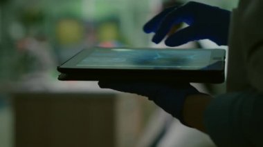Kimyager kadın DNA örneğini tablet kullanarak kontrol ediyor.