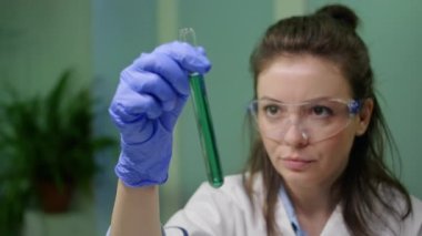 Bilim adamı kadının DNA örneğiyle birlikte test tüpüne baktığı yakın plan.