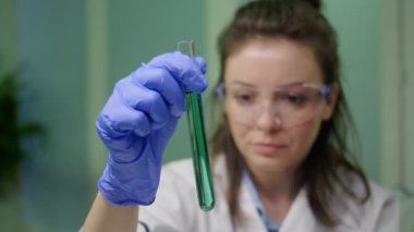 Kimyager kadın elinde DNA sıvısıyla test tüpü tutuyor.