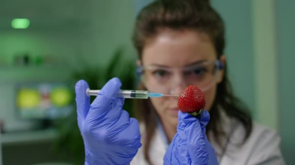 Nahaufnahme eines Biochemikers, der gesunde Erdbeeren mit dna-Flüssigkeit injiziert — Stockvideo