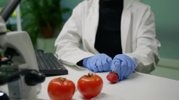 African chemist with medical glasses looking at strawberry injected with chemical pesticides — Stock Video