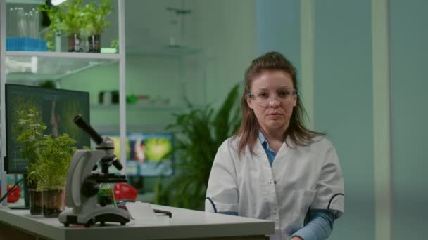 온라인 비디오를 보는 동안 흰색 코트를 입고 화학자 팀을 듣고 있는 식물학 자 여성의 사진 — 비디오