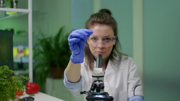 Biochemia naukowiec analizujący zieloną próbkę cieczy przy użyciu mikroskopu — Wideo stockowe