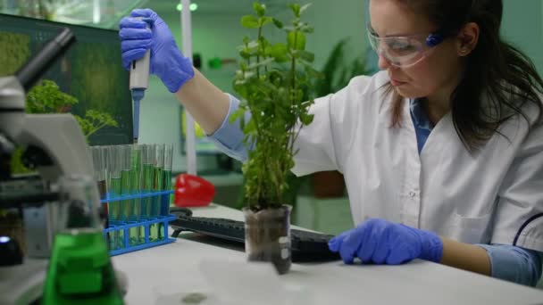 Biochimiste scientifique prenant du liquide vert avec micropieptte puttine sur sapling — Video