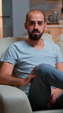 Serbest çalışan bir adam kanepeye oturmuş iş görüşmelerini kaydediyor.