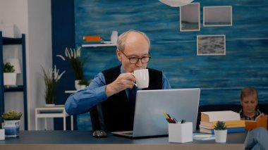 Üst düzey işadamı laptopun önünde oturmuş raporları okuyor.