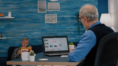 Orta yaşlı yaşlı bir adam iş grafiklerini analiz ediyor.