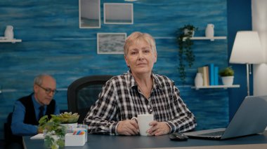 İş yerinde kameraya bakan yaşlı odaklı kadın.