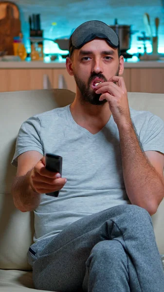 Homem adulto comendo pipocas em pé na frente da televisão — Fotografia de Stock