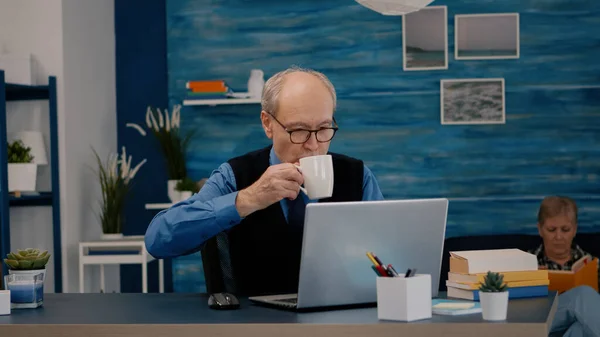 Senior rapporti di lettura uomo d'affari seduto davanti al computer portatile — Foto Stock