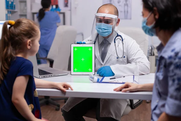 Médico con mascarilla facial y visera con tableta de pantalla verde PC en la oficina de examen —  Fotos de Stock