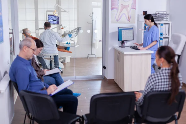 Folkmassa stomatologi väntrum med människor fylla formuläret — Stockfoto