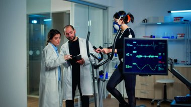 EKG sonuçlarını analiz eden bilim adamı, sporcunun kalp atışlarını inceleyen monitöre bakıyor.