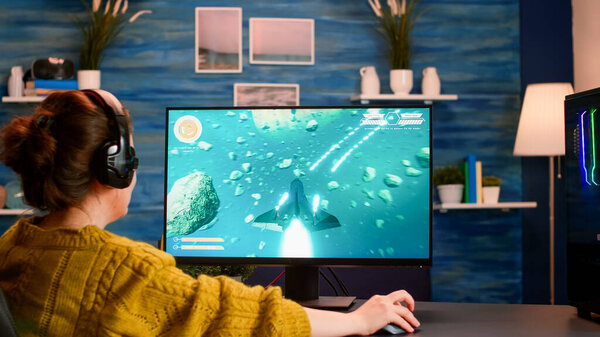 Over the shoulder woman gamer playing online shooter game