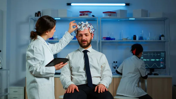 Paciente con auriculares de escaneo de ondas cerebrales discutiendo con investigador neurológico —  Fotos de Stock