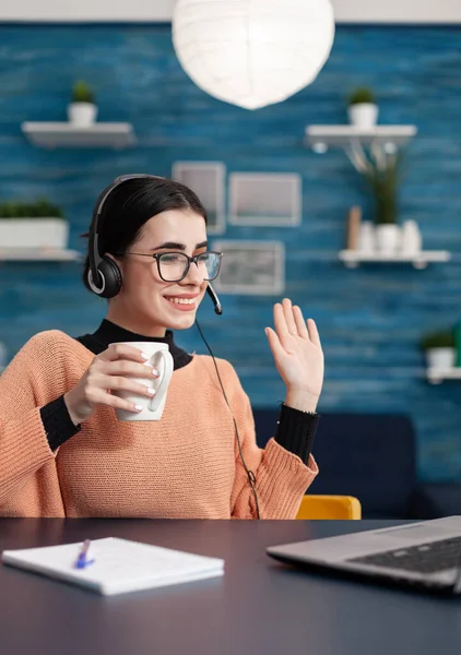 Studentka z okularami i filiżanką kawy w ręku wita swojego nauczyciela — Zdjęcie stockowe