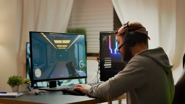 Cyber deporte gamer usando auriculares jugando en primera persona shooter videojuego — Foto de Stock