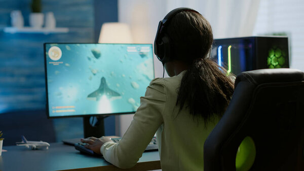 Competitive african gamer sitting on gaming chair, using headphone